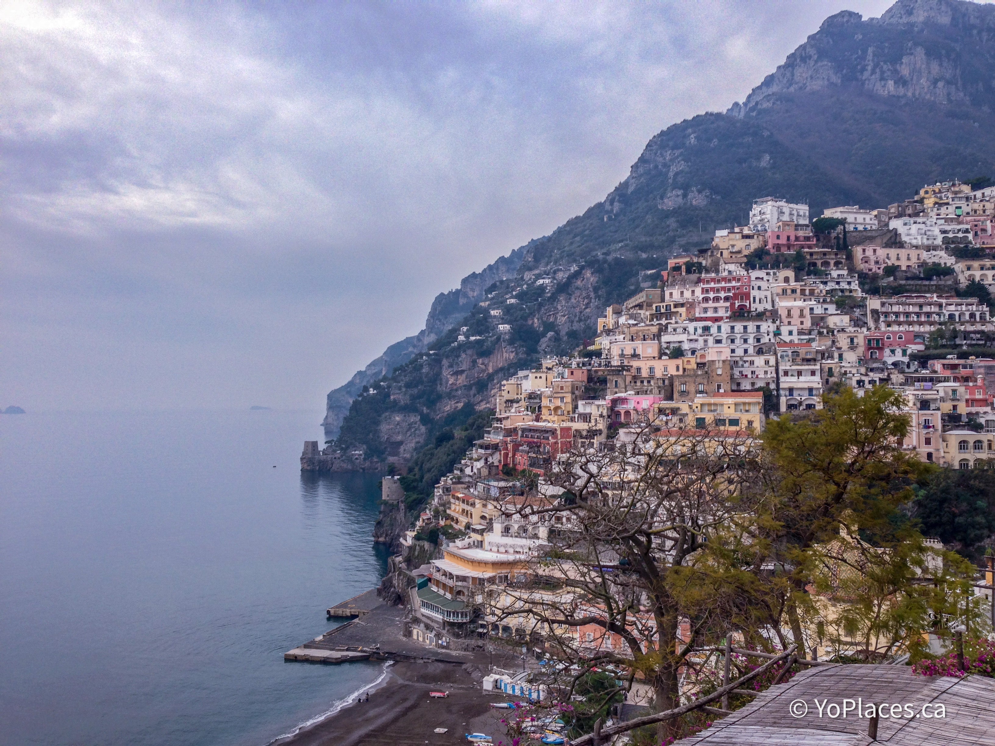 Hilly coastal town with buildings cascading down the mountain side, overlooking the ocean.