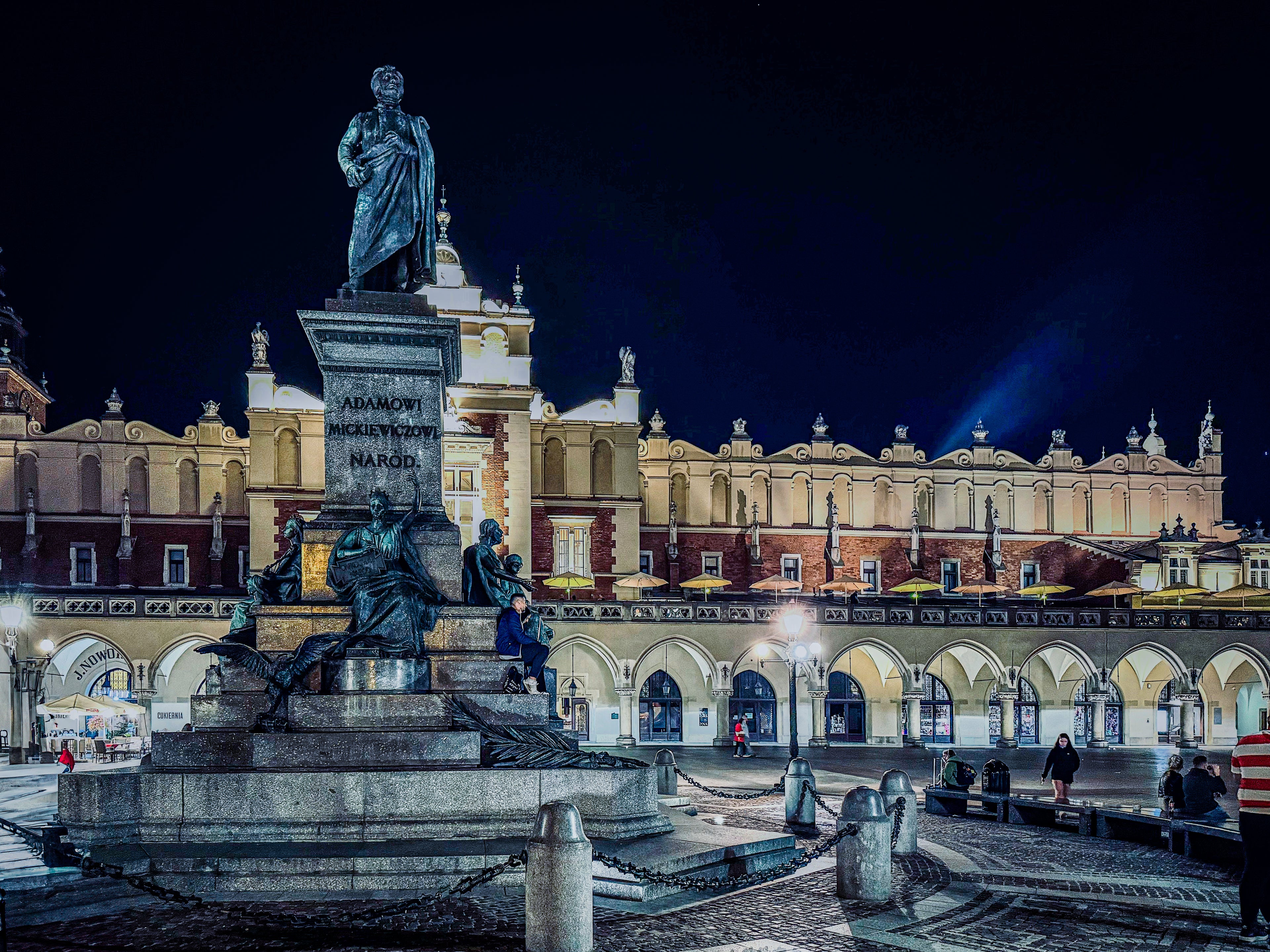 Statue in a city square at night with illuminated buildings