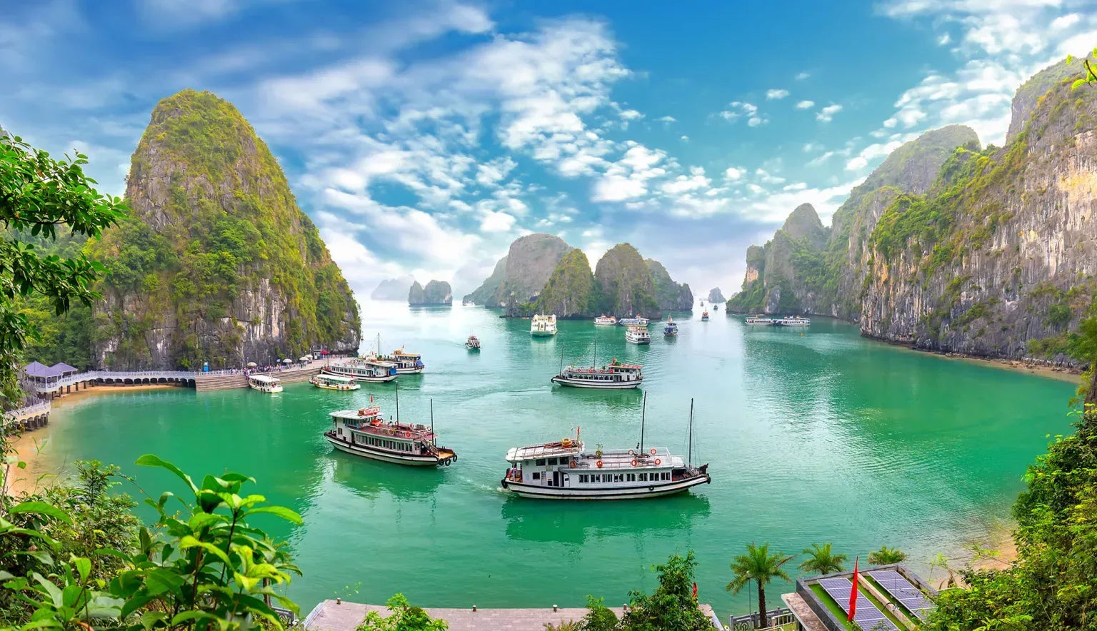 Scenic view of a tropical bay with limestone karsts and boats in Halong Bay, Vietnam.