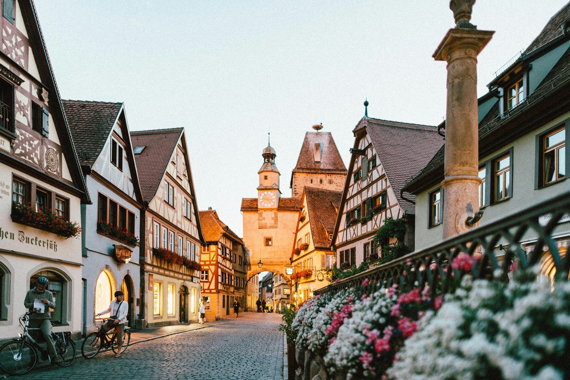 Cobbled street in a quaint European town with traditional architecture and flowers lining the path.