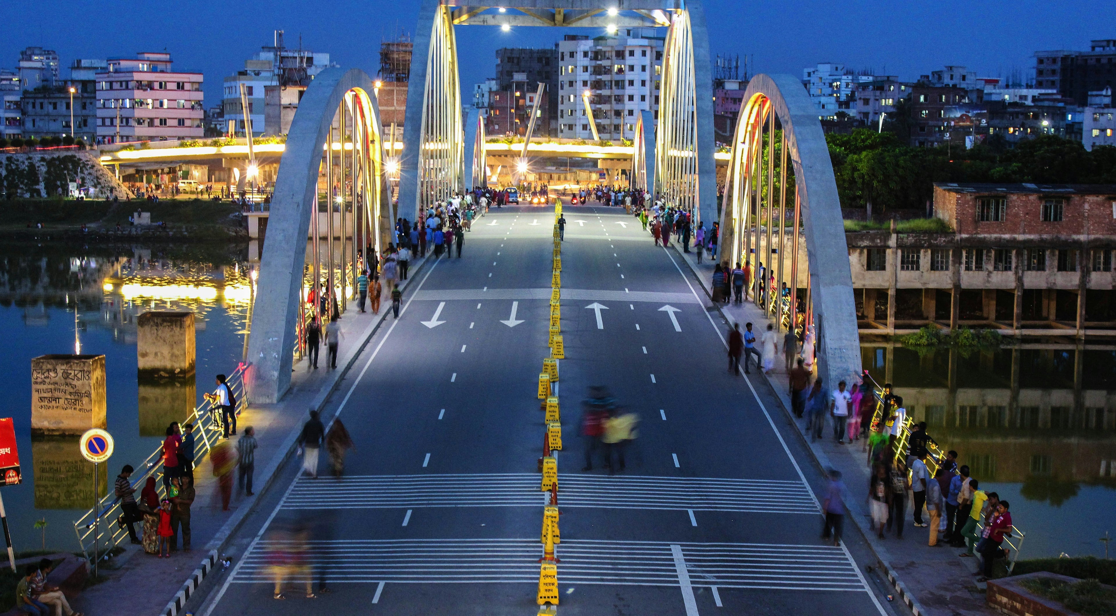 Modern bridge over a body of water with illuminated arches at night.